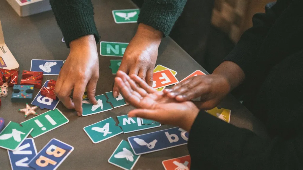 Hands matching sign language letter cards during an allied health learning activity.