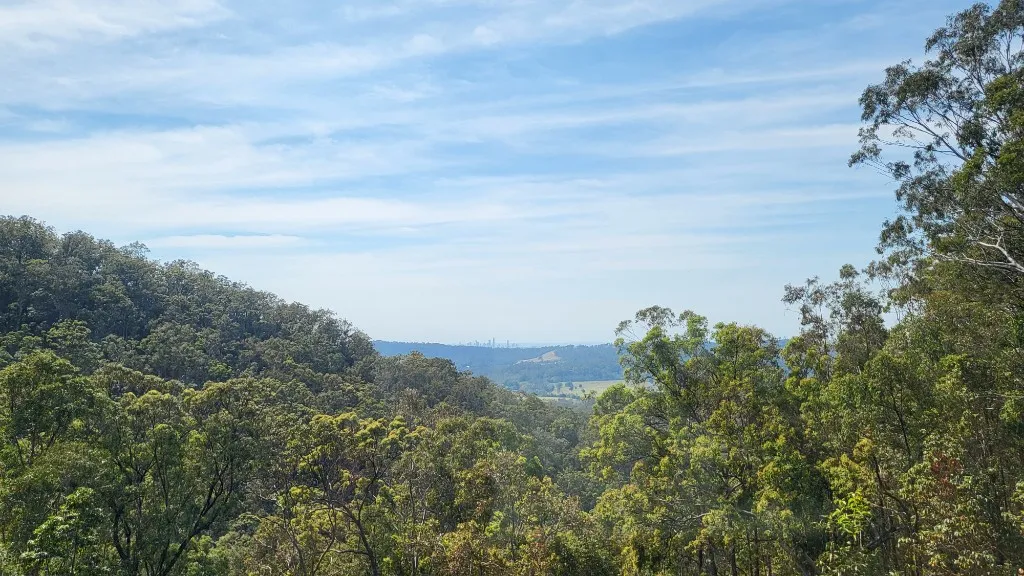 Green hills and forest across South East Queensland with Brisbane on the horizon.